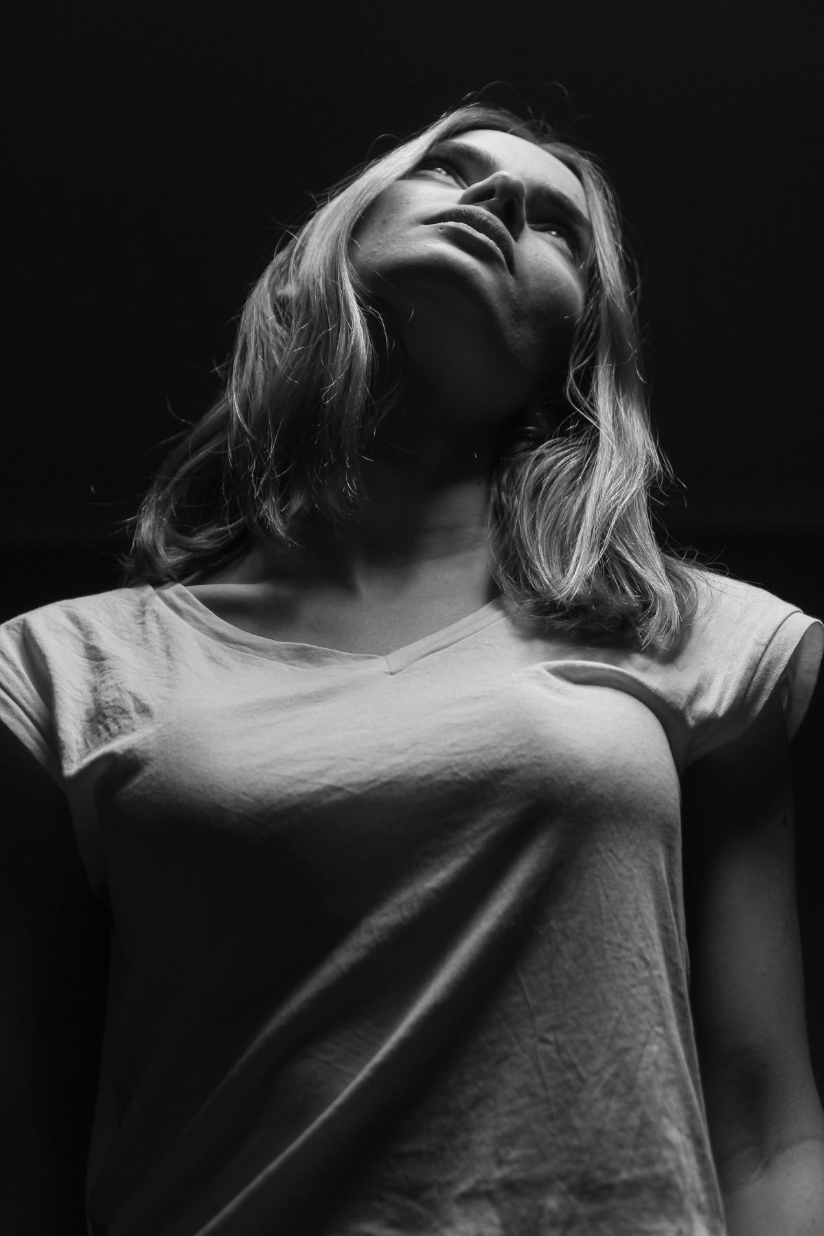 A black-and-white portrait of a woman with her head tilted back toward the light